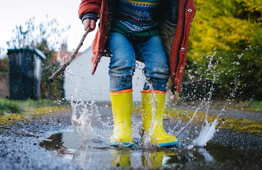 Kind springt in eine Pfütze